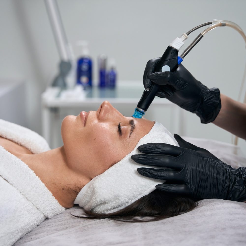 Beautician doing facial skin rejuvenation for pretty female